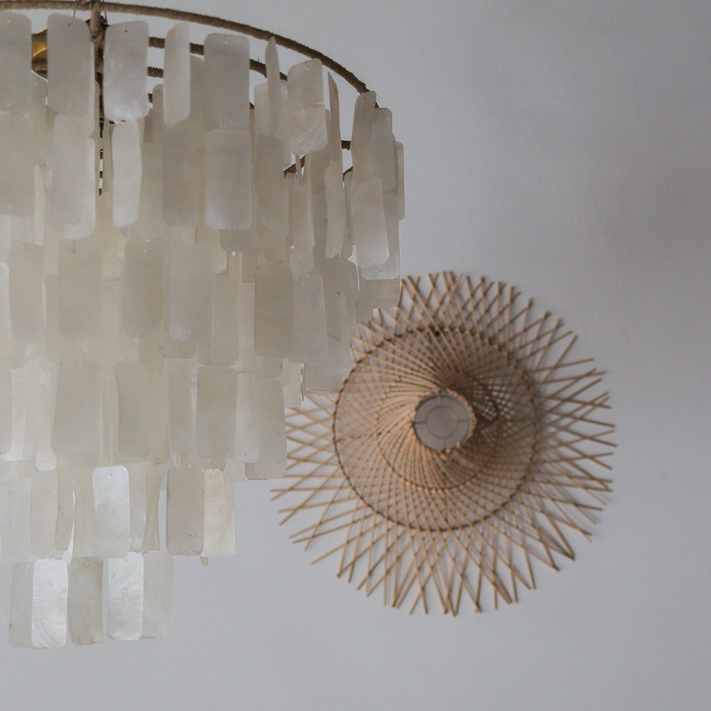 Decorative chandelier with a textured wall art piece on a plain background