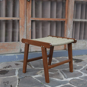 Handmade wooden stool with woven seat on stone patio, rustic Balinese furniture
