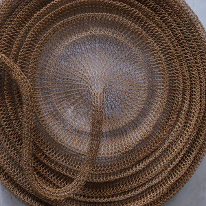 Handwoven rattan wall decor with intricate spiral pattern on neutral background