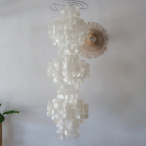 Handmade seashell chandelier with white capiz discs hanging in a minimalist room
