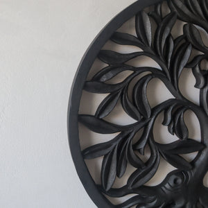 Hand-carved black wood wall art with leaf design on a white background