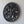 Hand-carved black wood wall art featuring a round tree of life design on a white wall.