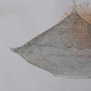 Handmade wire mesh lampshade with intricate woven design against a light background