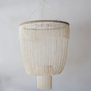 Handmade Balinese seashell chandelier with cascading white strands against a plain background.