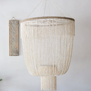 Large Balinese seashell chandelier with intricate bead strands, boho wall art in background