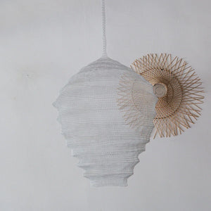 Handcrafted white woven pendant lamp with natural rattan accent against a white wall