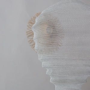 Handwoven white mesh rattan lampshade with intricate Balinese design on a neutral background
