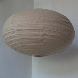 Handmade beige fabric pendant lamp with round shape, hanging in a minimalist interior