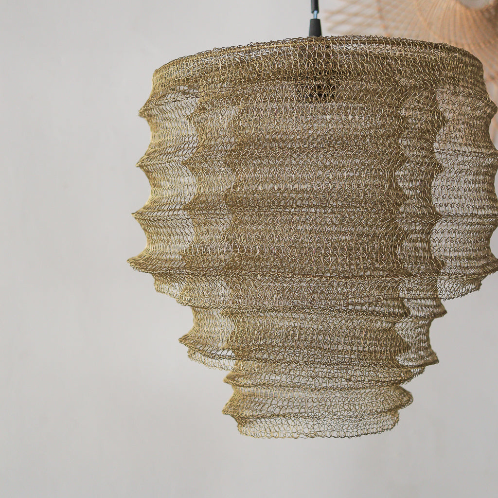 Textured gold pendant light against a neutral background