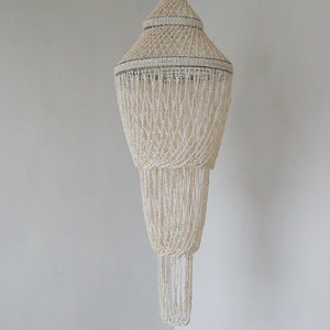 Handmade Balinese seashell chandelier with intricate beaded design against a white wall