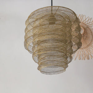 Handmade woven rattan pendant light with intricate spiral design against white wall.