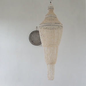 Handmade Balinese seashell chandelier hanging on a white wall, boho home decor