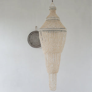Handcrafted Balinese seashell chandelier with intricate beaded design on a white wall
