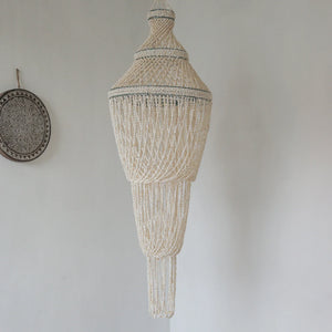 Handmade Balinese seashell chandelier with intricate beadwork hanging in a minimalist room