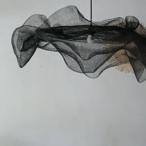 Modern black mesh pendant light with sculptural, airy design against a plain background