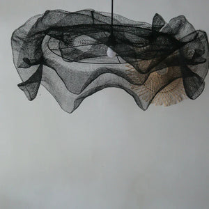 Modern black mesh pendant light with sculptural design against plain wall