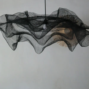 Modern black mesh pendant light with wavy sculptural design against a plain wall