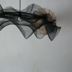 Modern black mesh pendant light with organic wave design on neutral wall