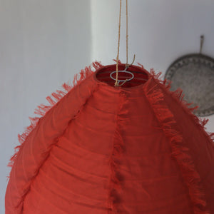 Red fabric pendant lamp with frayed edges, eco-friendly handmade decor, hanging indoors.