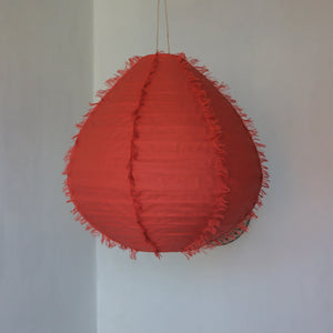 Handmade red hanging pendant lamp with fringe details against a plain wall