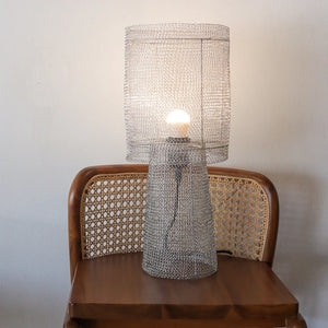 Handmade wire mesh table lamp on wooden chair with woven cane backrest