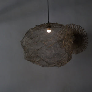 Handwoven rattan pendant light with organic shape hanging from ceiling against gray wall