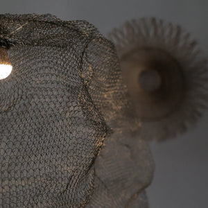 Close-up of handcrafted wire mesh lampshade with warm lighting, artisanal home decor