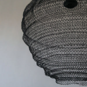 Handcrafted black wire chandelier with intricate mesh design against a neutral wall