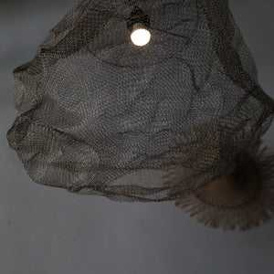 Handcrafted wire mesh pendant light with organic, sculptural design hanging from ceiling
