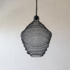 Handmade black mesh pendant light with organic, sculptural design hanging against a plain wall