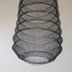 Handmade black wire mesh pendant light with intricate woven pattern against plain background