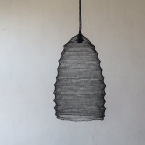 Handwoven black wire pendant lamp with textured design against a neutral wall.