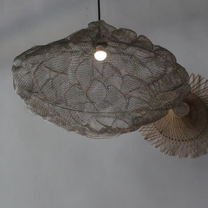 Handwoven rattan pendant light with intricate leaf pattern, hanging from a ceiling