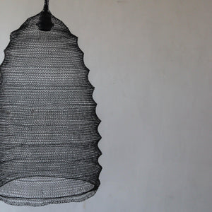 Handcrafted black wire mesh pendant light with sculptural design on plain wall