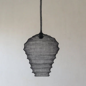 Handmade black wire pendant lamp with scalloped edges hanging against a neutral wall