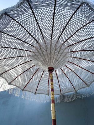 Handcrafted Balinese parasol with detailed macrame canopy and wooden pole outdoors