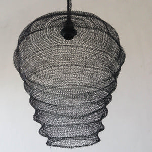 Black wire mesh pendant light with organic, handcrafted design against a plain wall