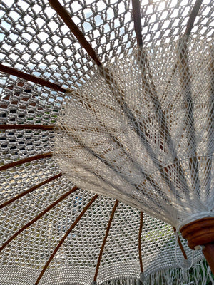 Close-up of handmade Balinese macrame parasol with natural wooden frame outdoors