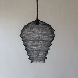 Handmade black wire pendant lamp with sculpted organic shape against a plain wall