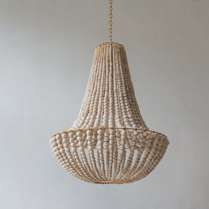 Handmade wood bead chandelier with gold chain against a neutral wall, Balinese home decor