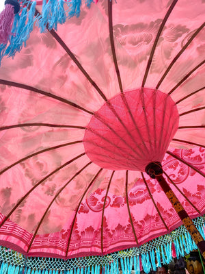 Pink Balinese umbrella interior showcasing intricate designs and vibrant colors, handmade in Bali, Indonesia.