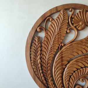 Hand-carved wooden wall art with intricate leaf design on a white background