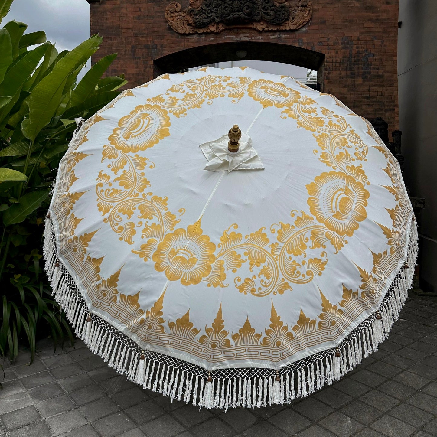Decorative white umbrella with gold patterns on a tiled floor.