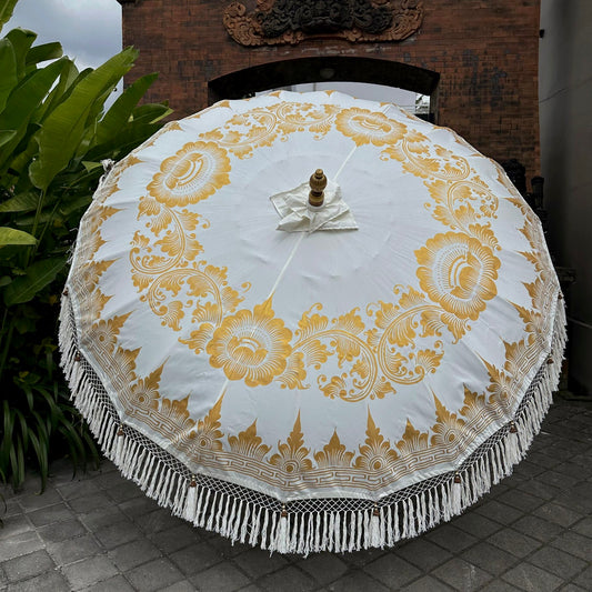 Decorative white umbrella with gold patterns on a tiled floor.