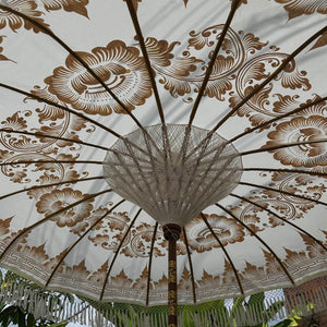 Handmade Balinese umbrella with intricate floral patterns and bamboo spokes outdoors