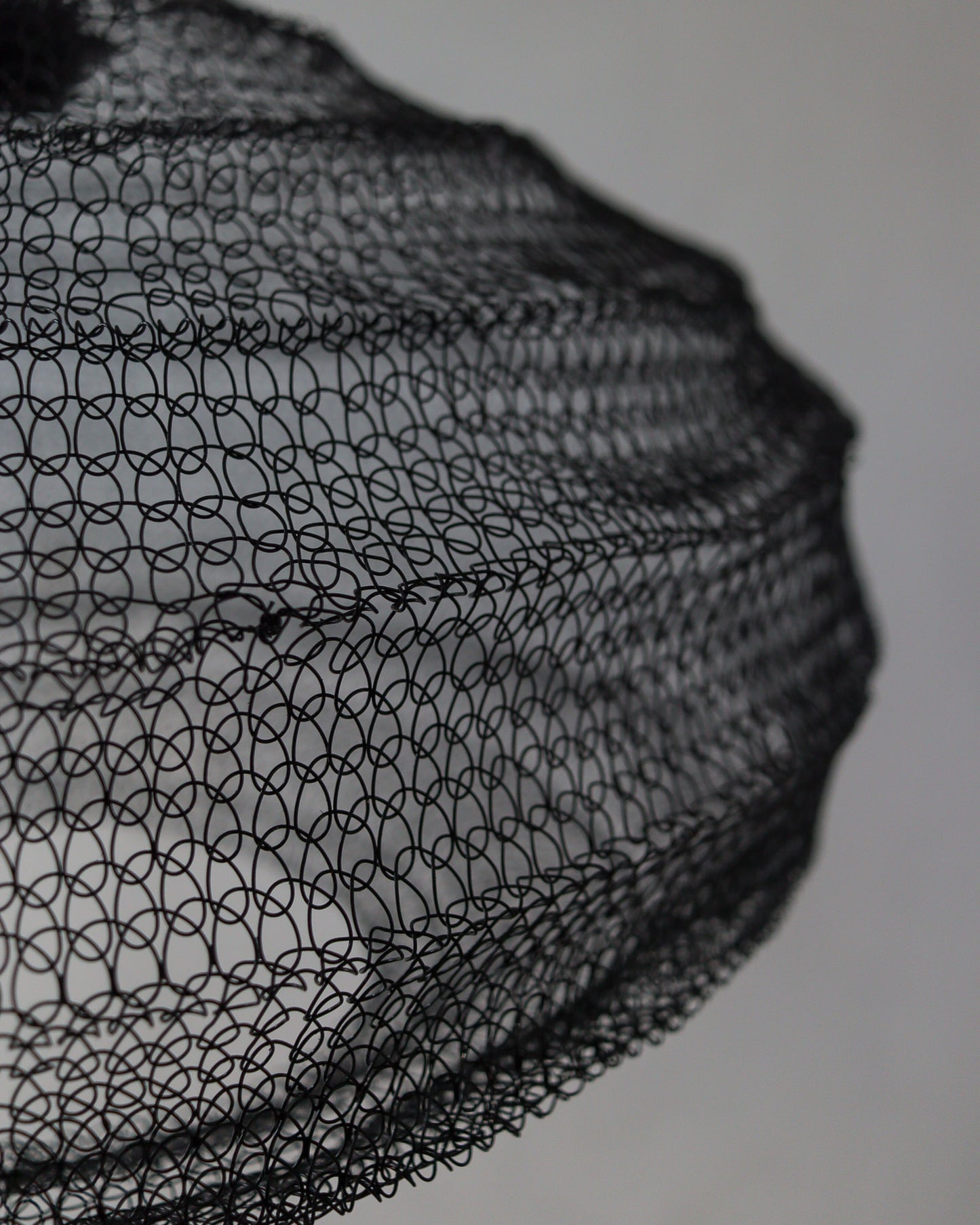 Close-up of handcrafted black wire mesh chandelier showcasing intricate design details.