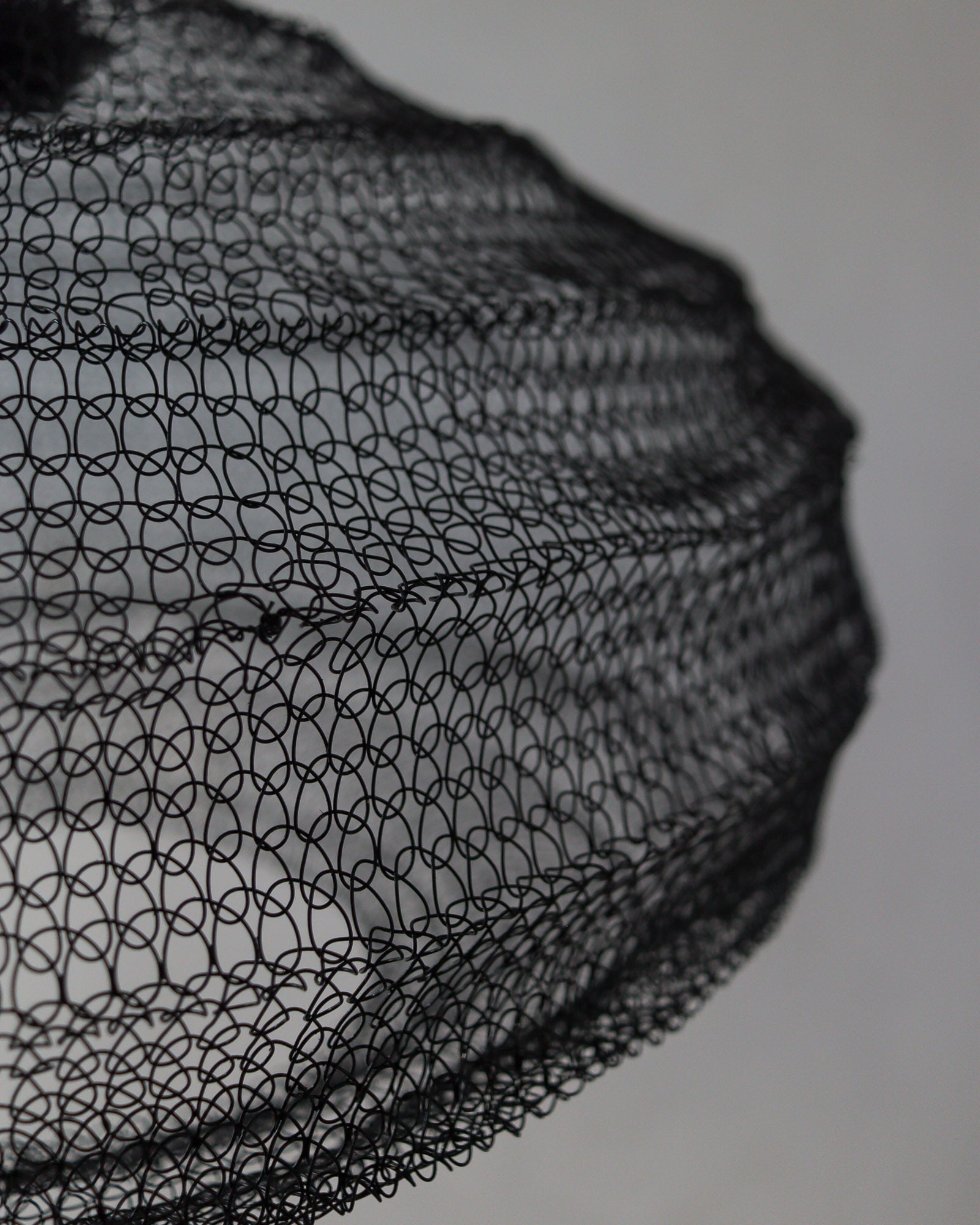 Close-up of handcrafted black wire mesh chandelier showcasing intricate design details.