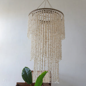 Handmade Balinese seashell chandelier with cascading shell strands in a minimalist room