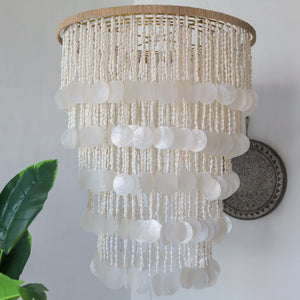 Handmade seashell chandelier with natural beads, hanging in a bright, modern room