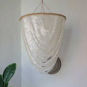 Handmade Balinese seashell chandelier with cascading white shells in a minimalist room
